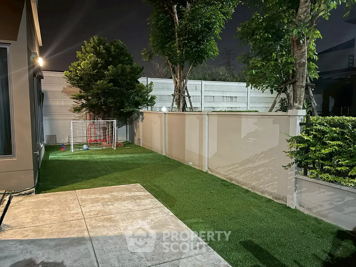 Spacious backyard with artificial grass and a small soccer goal, perfect for family activities.