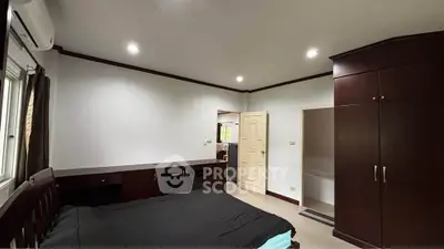 Spacious bedroom with dark wood furniture and ample natural light