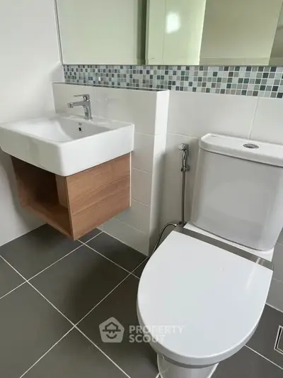 Modern bathroom with sleek sink and toilet, featuring stylish tile accents.