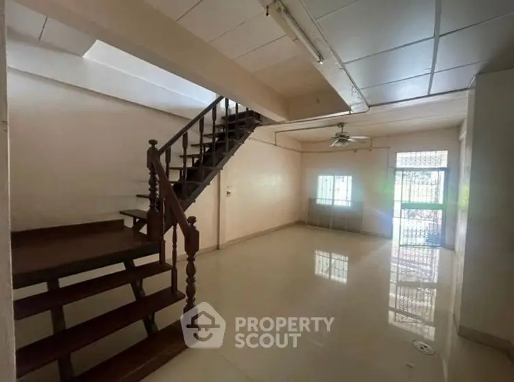 Spacious living room with staircase and large window, ideal for family gatherings.