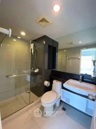 Modern bathroom with glass shower and sleek fixtures in a contemporary apartment.