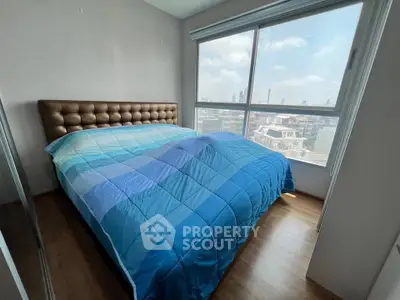 Cozy bedroom with large window offering stunning city views and natural light.
