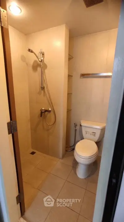 Compact bathroom with shower and toilet in modern apartment.