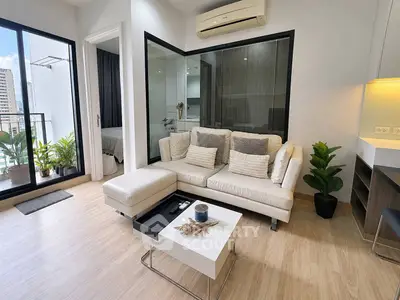 Modern living room with stylish decor and balcony view in urban apartment.