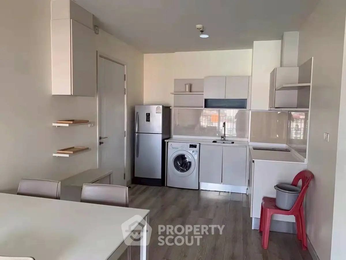 Modern kitchen with washing machine and sleek cabinetry in compact apartment