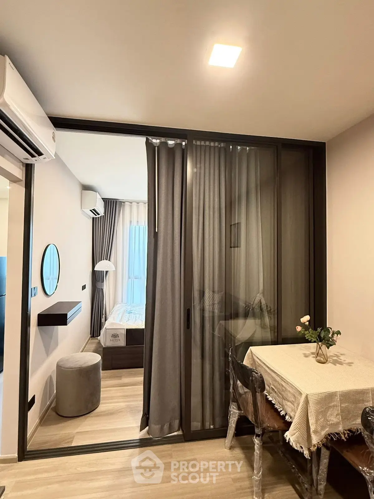 Modern apartment interior with cozy dining area and sliding glass doors leading to a stylish bedroom.