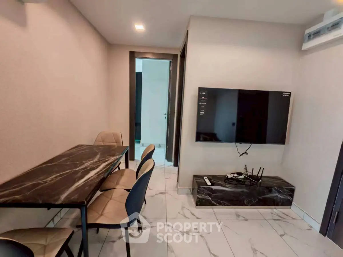 Modern living room with marble dining table and wall-mounted TV, sleek design and elegant decor.