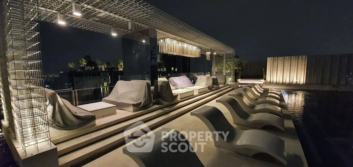Luxurious rooftop pool area with modern lounge chairs and ambient lighting at night.