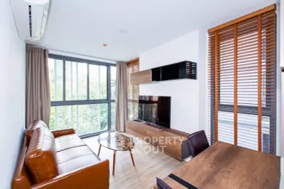 Modern living room with large windows, stylish furniture, and natural light.