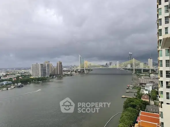 Stunning river view from high-rise apartment with cityscape and bridge under cloudy sky.