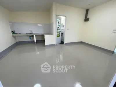 Spacious empty room with tiled floor and simple kitchen setup