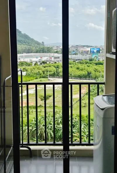 Scenic balcony view with lush greenery and distant hills from a high-rise apartment.