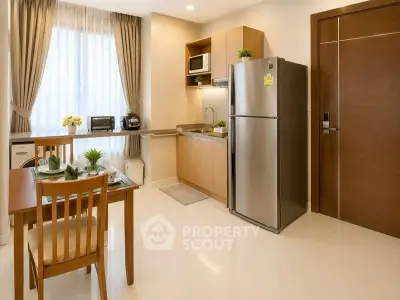 Modern kitchen with stainless steel fridge and dining area in cozy apartment.