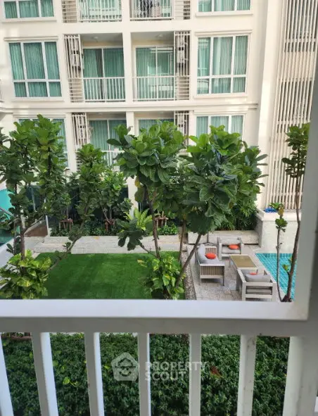 Modern apartment building with lush garden and pool view, perfect for urban living.