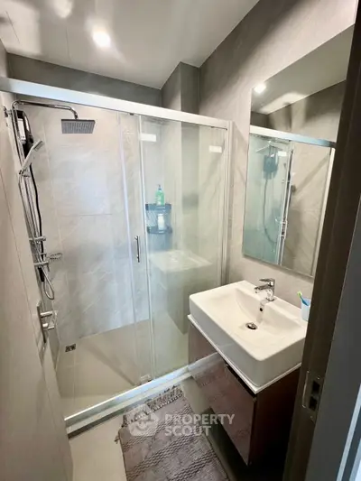 Modern bathroom with sleek shower and stylish sink in contemporary apartment.