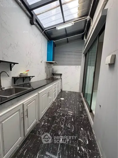 Modern kitchen with sleek black and white design, featuring ample counter space and natural light.