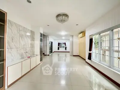 Spacious living room with elegant chandelier and large windows in modern home.