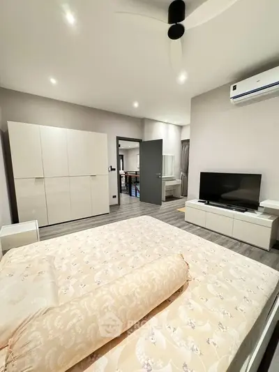 Spacious modern bedroom with elegant furnishings and neutral tones, featuring a large wardrobe and sleek TV unit.