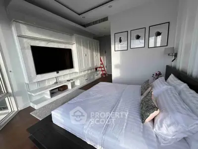 Luxurious bedroom with modern decor and large TV, perfect for relaxation and comfort.