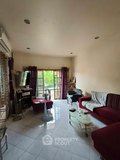 Spacious living room with modern furniture and large window overlooking greenery.