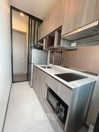 Modern compact kitchen with sleek cabinetry and built-in appliances in a stylish apartment.