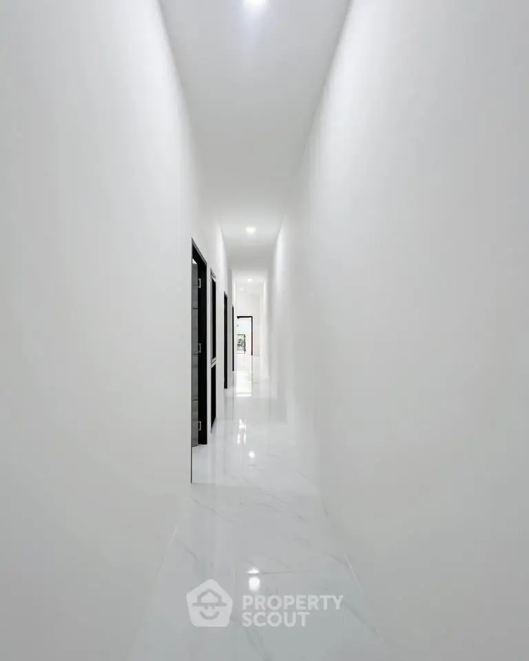 Sleek modern corridor with glossy white marble flooring and minimalist design.