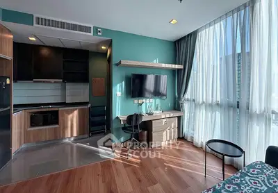 Modern studio apartment with sleek kitchen and large windows offering city views.
