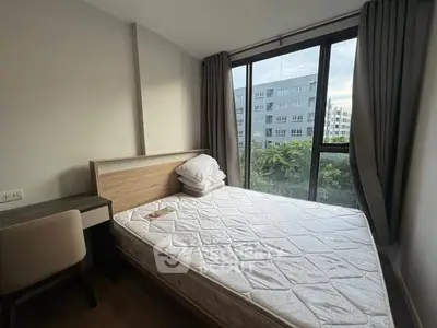 Cozy bedroom with large window offering a scenic view, perfect for relaxation and comfort.