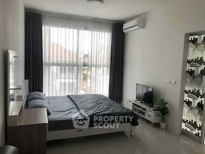 Modern bedroom with large window, stylish decor, and natural light in a contemporary apartment.