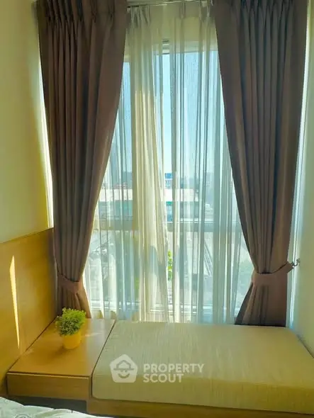 Cozy bedroom with large window and elegant curtains, offering a bright and inviting atmosphere.