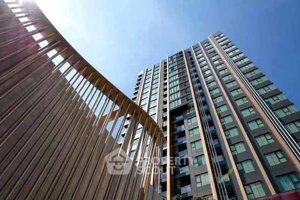Modern high-rise building with unique architectural design and clear blue sky backdrop.