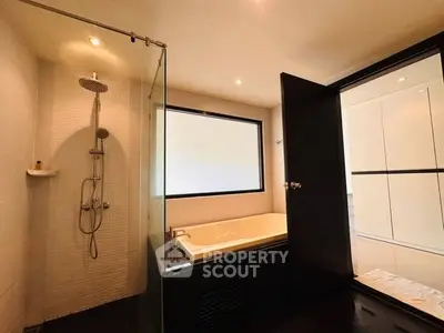 Modern bathroom with glass shower and bathtub, sleek design.