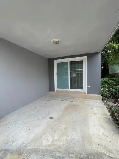 Spacious covered patio area with sliding glass doors and garden view, perfect for outdoor relaxation.
