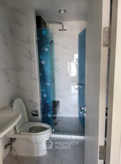 Modern bathroom with sleek marble tiles and glass shower enclosure.