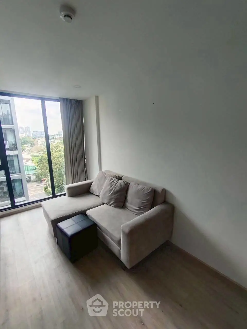 Modern living room with cozy sofa and large window offering city view.