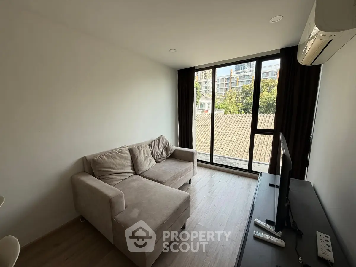 Modern living room with large window and cozy sofa in urban apartment.