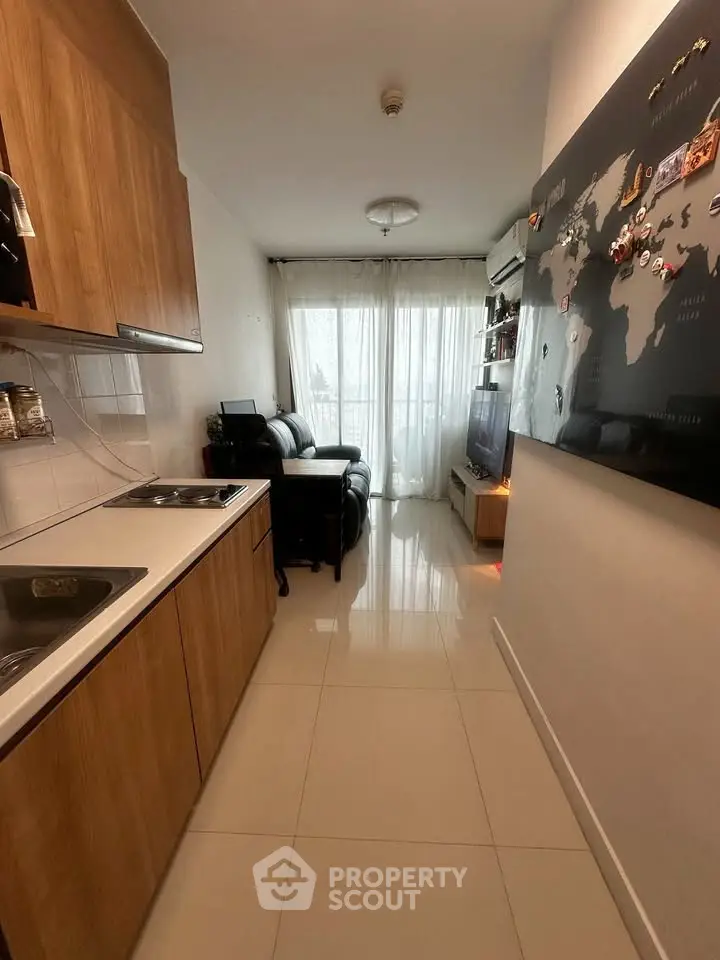 Modern apartment with sleek kitchen and cozy living area, featuring a world map wall decor and natural light.