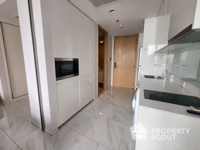 Sleek modern kitchen with built-in stainless steel appliances, glossy white cabinetry, and marble flooring, reflecting a luxurious urban lifestyle.