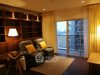 Cozy living room with balcony view, featuring plush seating and warm lighting.