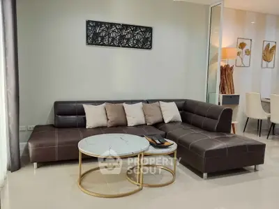Modern living room with stylish brown leather sectional sofa and chic round coffee tables.