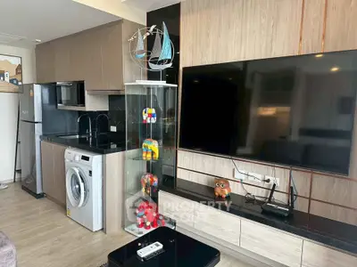 Modern living room with sleek kitchen, large TV, and stylish decor in a contemporary apartment.