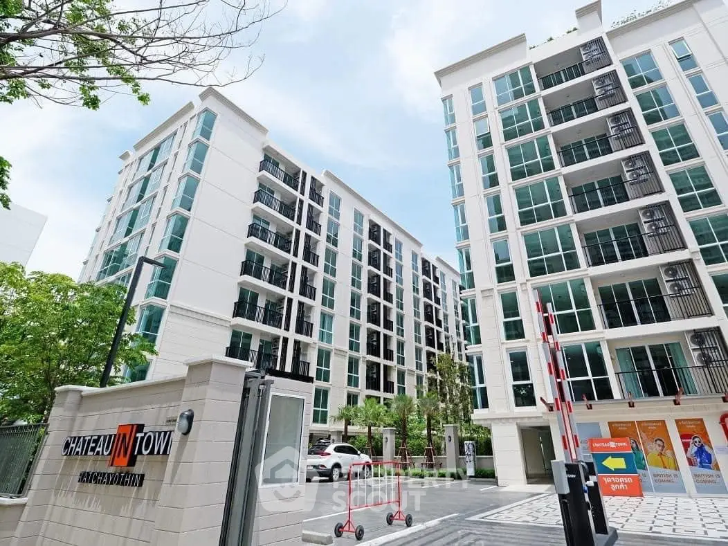 Modern condominium building with lush greenery and secure entrance in urban setting.