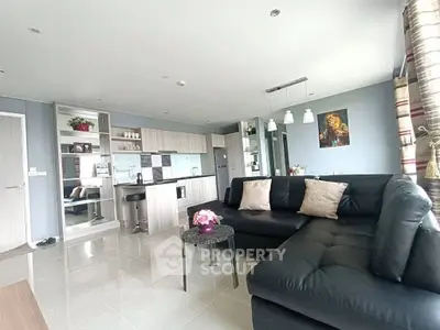 Modern living room with sleek kitchen, stylish decor, and cozy seating area.