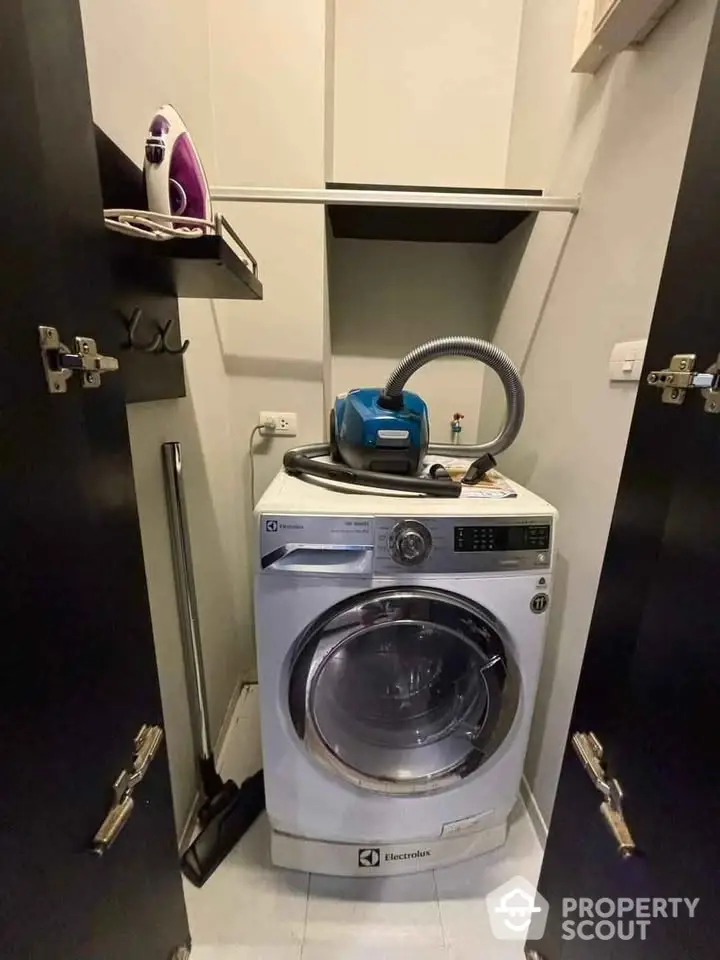 Compact laundry area with washing machine and cleaning tools in modern home