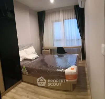 Cozy bedroom with modern furnishings and large window for natural light.