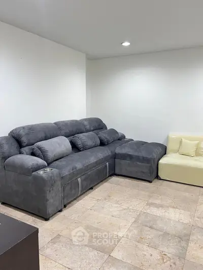 Spacious living room with plush gray sectional sofa and tiled flooring