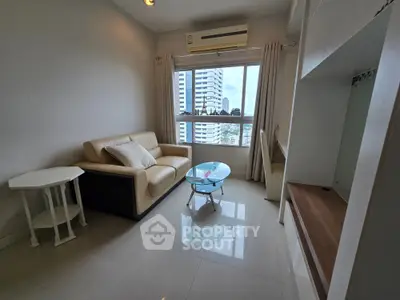 Modern living room with city view, featuring a cozy sofa and sleek glass coffee table.