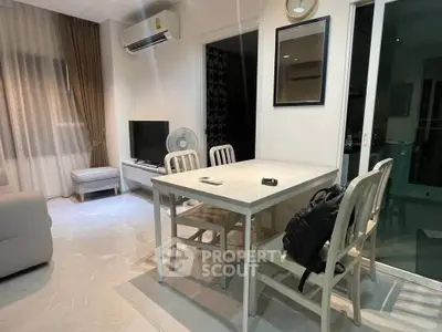Modern dining area with sleek table and chairs, adjacent to cozy living room, featuring air conditioning and natural light.