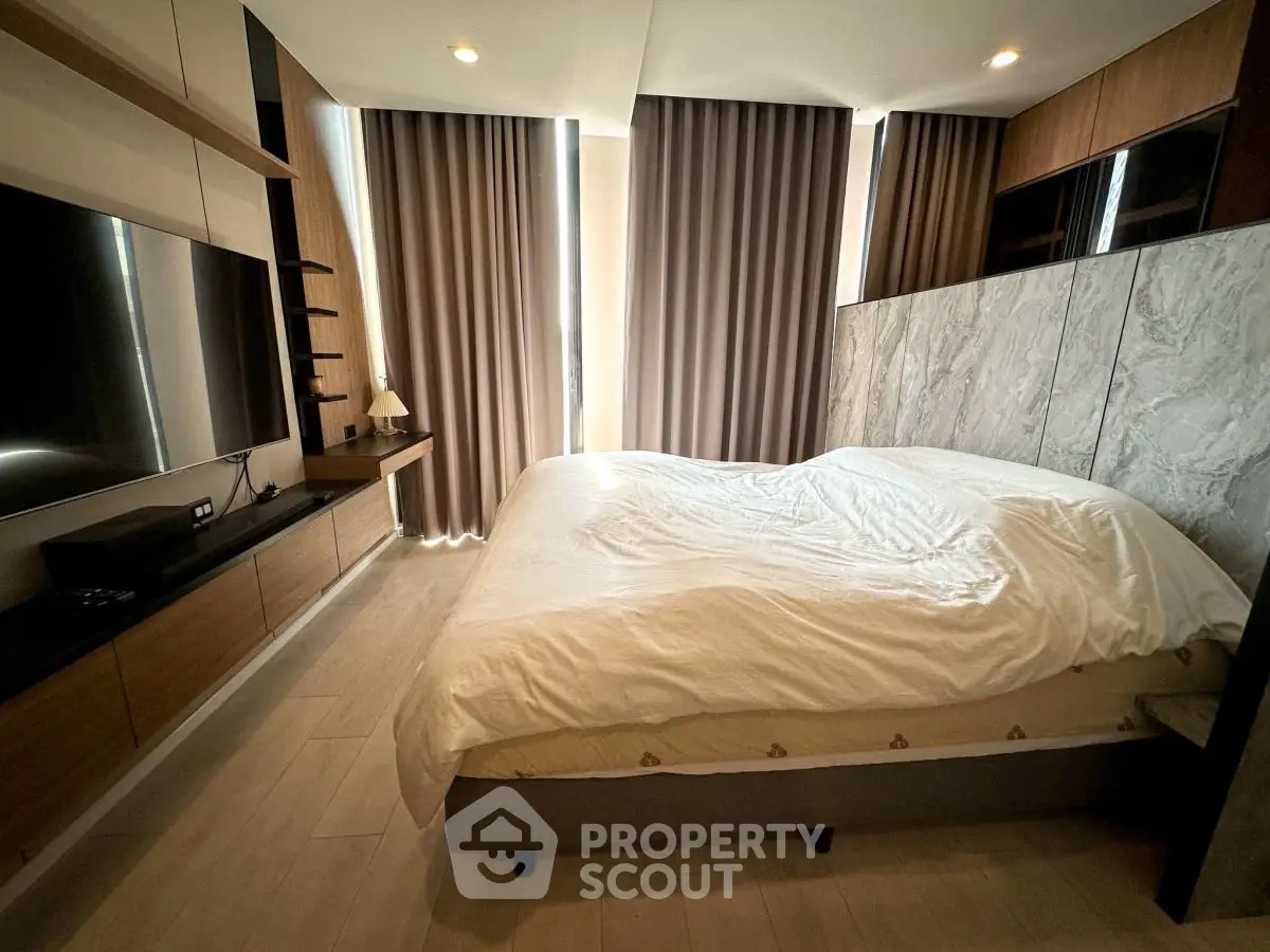 Modern bedroom with large bed, stylish curtains, and wall-mounted TV in a cozy apartment.