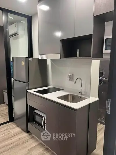 Modern compact kitchen with sleek cabinetry and stainless steel appliances in a stylish apartment.